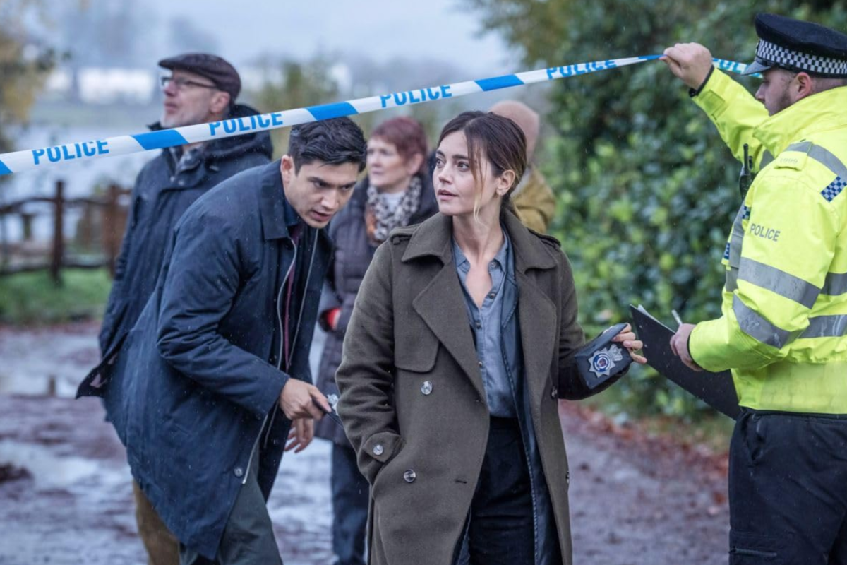 a woman in trench coat holding a police tape over a group of people